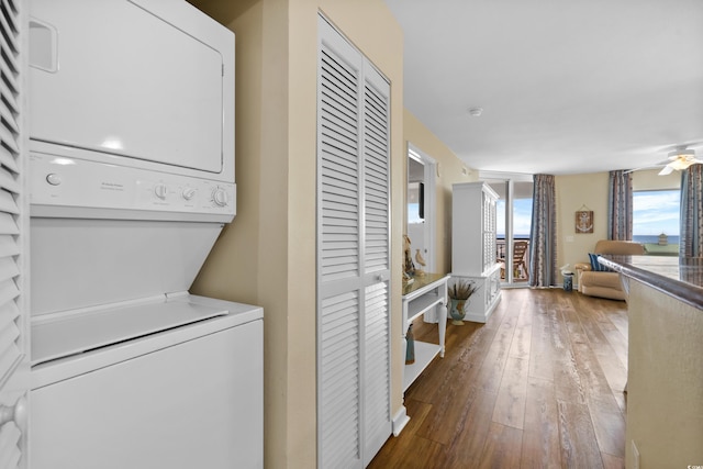 washroom with ceiling fan, stacked washer and dryer, and dark hardwood / wood-style flooring