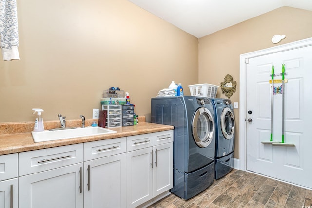 laundry area featuring sink, washer and clothes dryer, hardwood / wood-style flooring, and cabinets