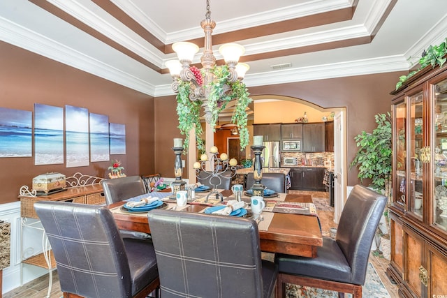 dining space with light hardwood / wood-style floors, a notable chandelier, and ornamental molding