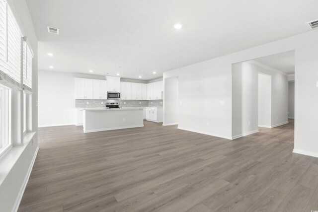 unfurnished living room featuring plenty of natural light and dark wood-type flooring