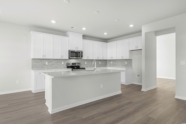 kitchen featuring backsplash, a center island with sink, dark hardwood / wood-style floors, white cabinetry, and stainless steel appliances