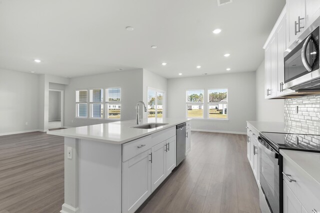 kitchen with white cabinetry, a kitchen island with sink, sink, and stainless steel appliances