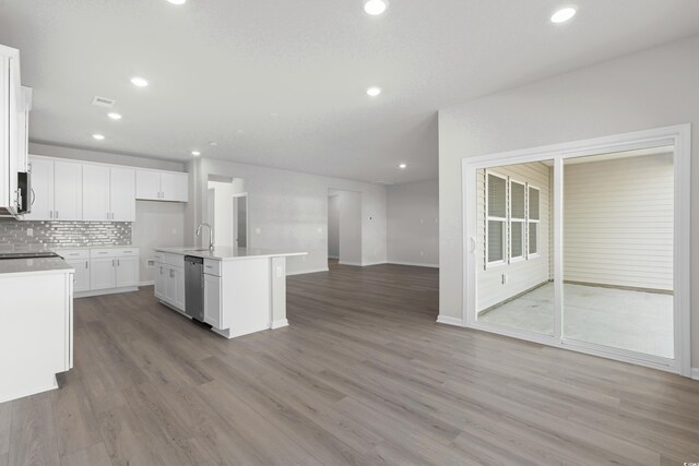 kitchen featuring backsplash, a kitchen island with sink, dishwasher, and white cabinets