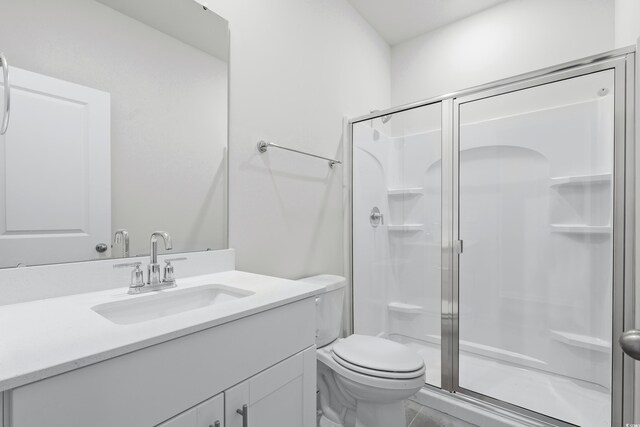 bathroom featuring vanity, toilet, and a shower with door