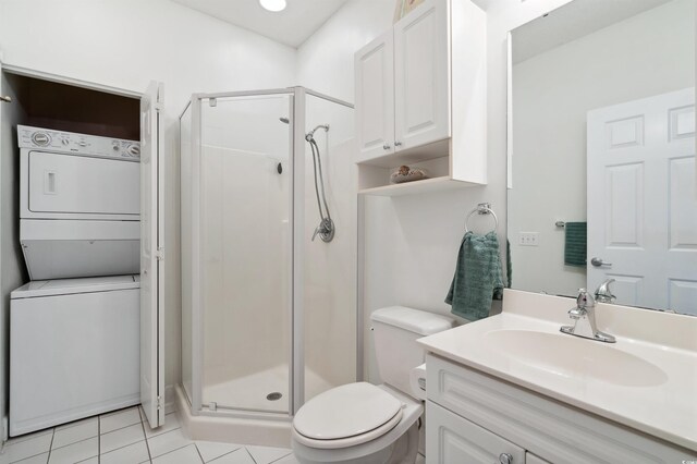 bathroom with stacked washing maching and dryer, toilet, a shower with shower door, vanity, and tile patterned floors