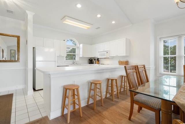 kitchen with white appliances, plenty of natural light, and white cabinets