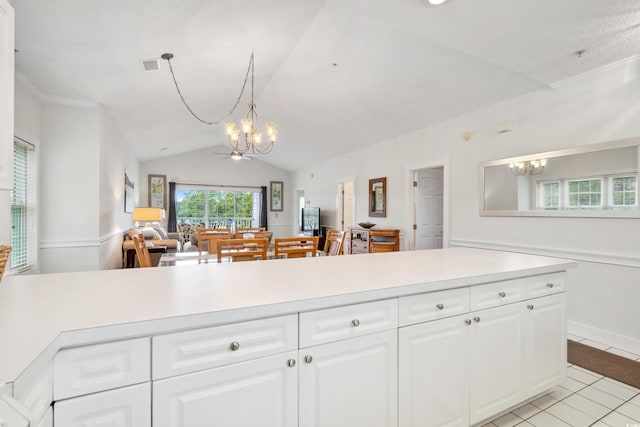 kitchen featuring lofted ceiling, white cabinets, light tile patterned floors, pendant lighting, and a notable chandelier