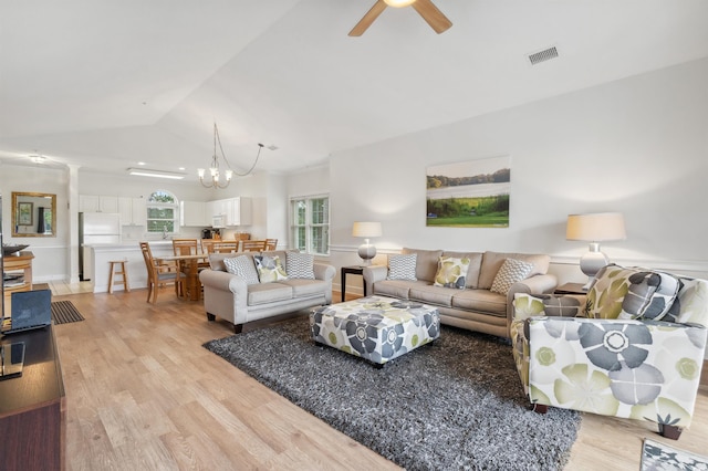 living room featuring lofted ceiling, ceiling fan with notable chandelier, and light wood-type flooring