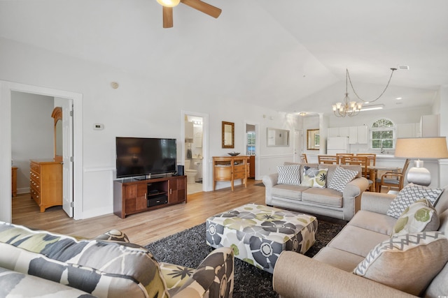 living room featuring high vaulted ceiling, ceiling fan with notable chandelier, and light wood-type flooring