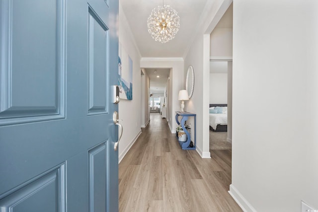 hall with light hardwood / wood-style floors, a chandelier, and crown molding