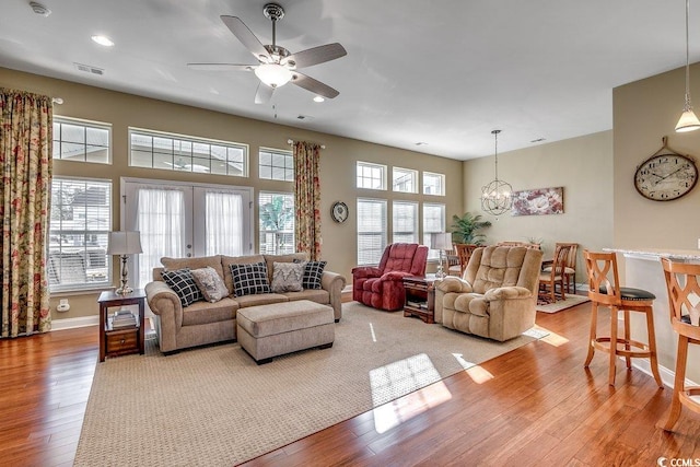 living room featuring french doors, light hardwood / wood-style flooring, and ceiling fan with notable chandelier