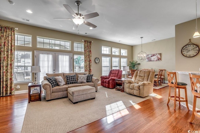 living room featuring ceiling fan with notable chandelier, recessed lighting, baseboards, wood finished floors, and visible vents