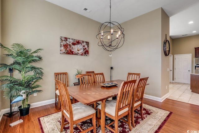 dining space with baseboards, visible vents, an inviting chandelier, and light wood finished floors