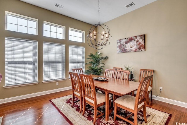 dining space featuring baseboards, a notable chandelier, wood finished floors, and visible vents