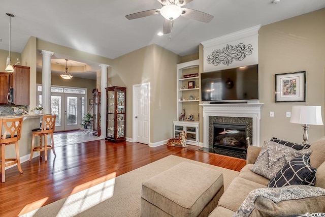 living area with baseboards, a ceiling fan, ornate columns, and dark wood-style floors