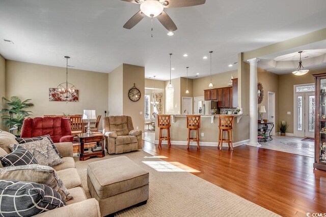 living area with baseboards, ornate columns, ceiling fan, and wood finished floors