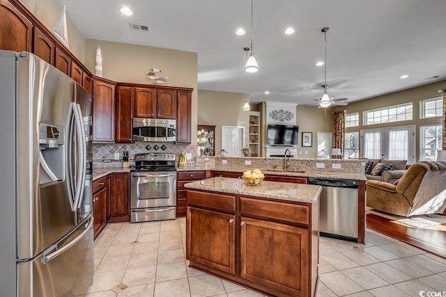 kitchen featuring light tile patterned flooring, appliances with stainless steel finishes, a sink, a peninsula, and open floor plan
