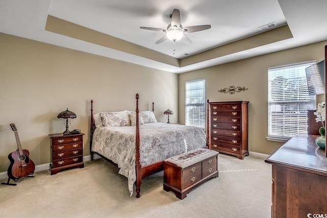 bedroom featuring baseboards, visible vents, a tray ceiling, and light colored carpet