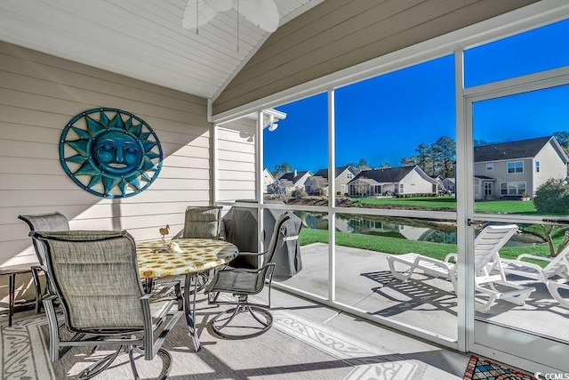 sunroom / solarium featuring a water view, a ceiling fan, and a residential view