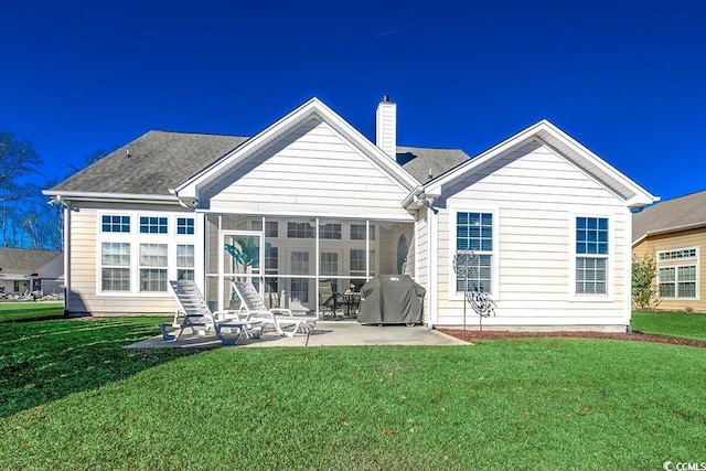 rear view of property with a sunroom, a patio area, a yard, and a chimney