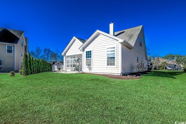 rear view of house featuring a lawn, a chimney, and a patio