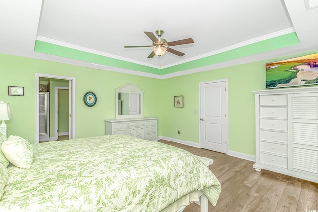 bedroom featuring baseboards, a tray ceiling, ornamental molding, wood finished floors, and a ceiling fan