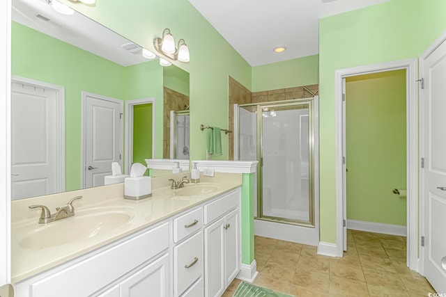 full bathroom featuring a shower stall, double vanity, tile patterned floors, and a sink