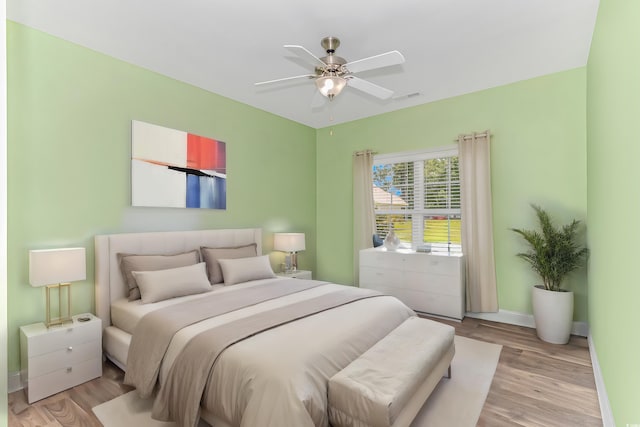 bedroom with a ceiling fan, visible vents, baseboards, and light wood-type flooring