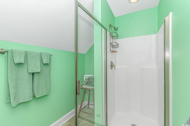 full bath featuring baseboards, a stall shower, and vaulted ceiling