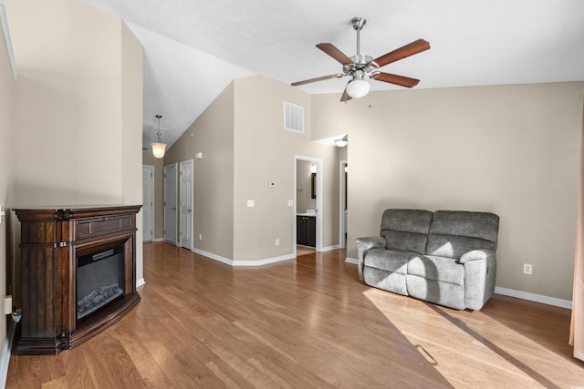 sitting room featuring ceiling fan, wood finished floors, visible vents, baseboards, and a glass covered fireplace