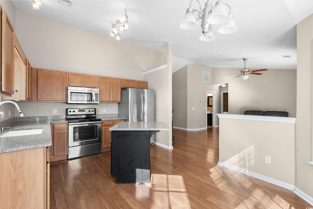 kitchen with stainless steel appliances, a sink, open floor plan, a center island, and pendant lighting