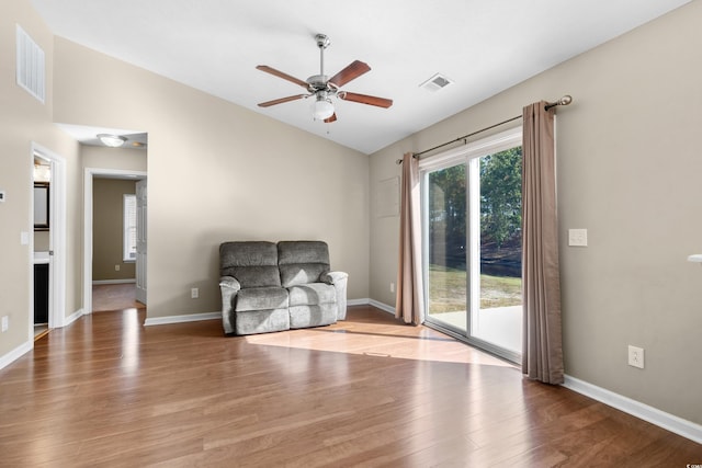 sitting room featuring light wood-style floors, visible vents, and vaulted ceiling