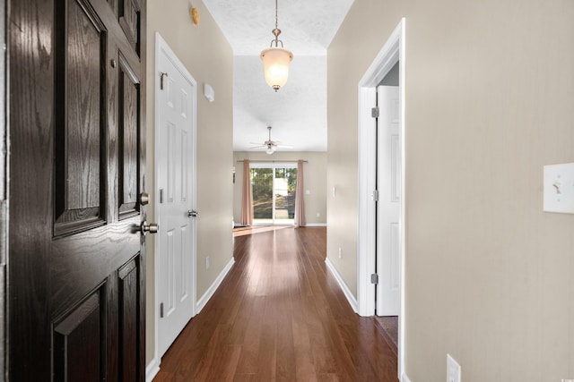 hall with dark wood-style flooring and baseboards