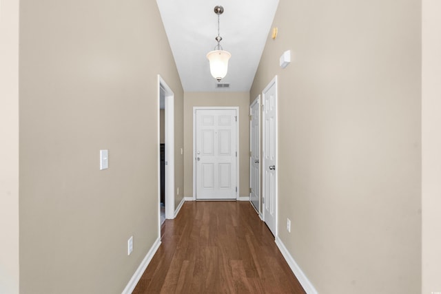 hallway with dark wood-type flooring, visible vents, and baseboards