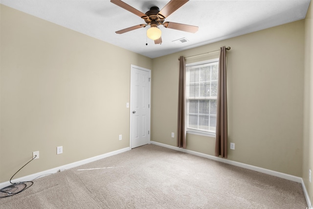 carpeted spare room with visible vents, ceiling fan, and baseboards