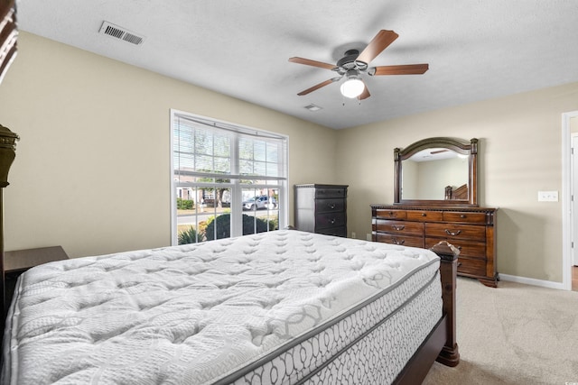 bedroom with light carpet, ceiling fan, visible vents, and baseboards