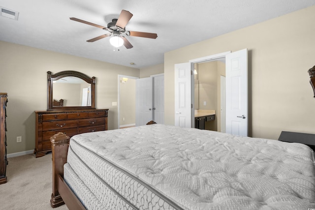 bedroom featuring baseboards, visible vents, light colored carpet, ensuite bath, and ceiling fan