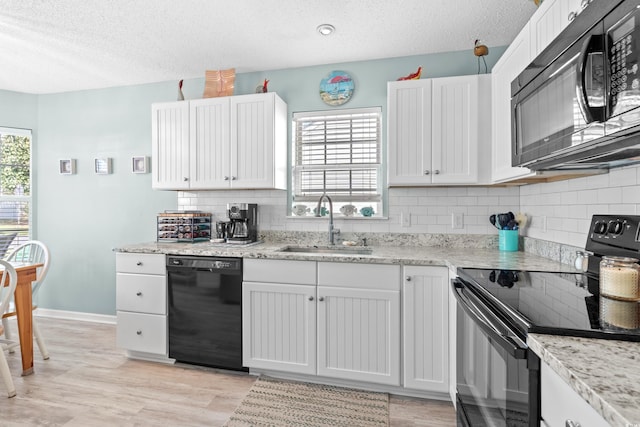 kitchen featuring a textured ceiling, black appliances, a sink, and a wealth of natural light