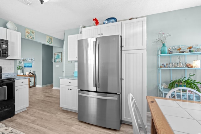 2169 Wedgewood Dr, Longs, SC 29568 - kitchen with black appliances, white cabinets, light wood-style flooring, backsplash, and a textured ceiling