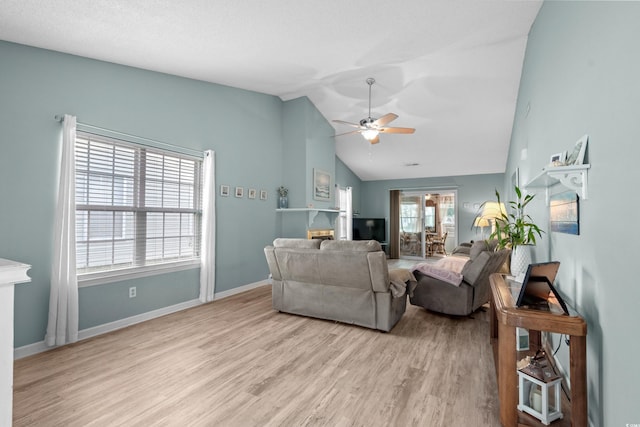 living area with a fireplace, wood finished floors, a ceiling fan, baseboards, and vaulted ceiling