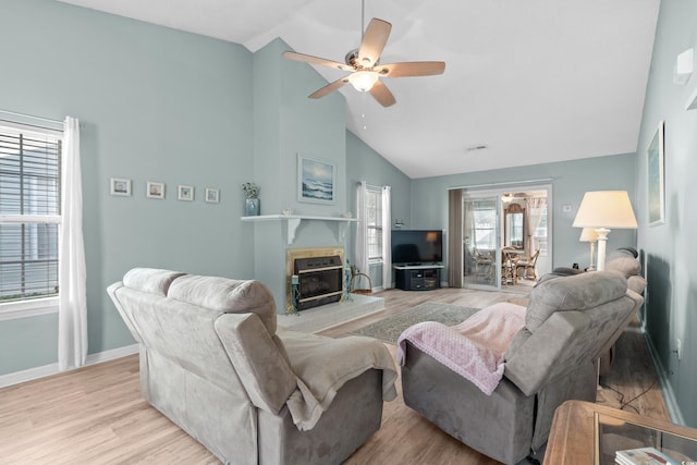 living room featuring baseboards, ceiling fan, wood finished floors, a brick fireplace, and high vaulted ceiling