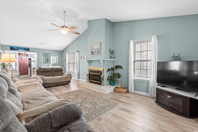 living room with a tile fireplace, wood finished floors, a ceiling fan, baseboards, and vaulted ceiling