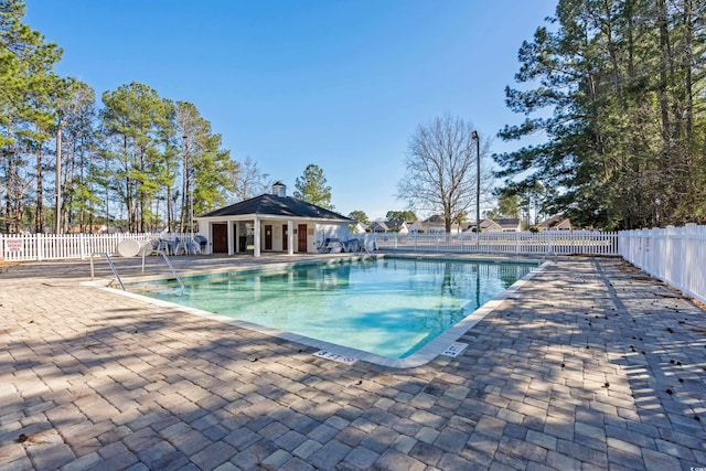 pool featuring a patio area, fence, and an outdoor structure