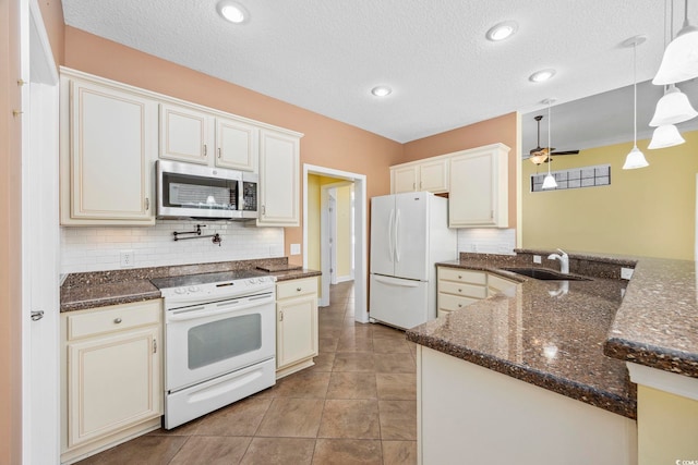 kitchen with white appliances, sink, pendant lighting, and kitchen peninsula