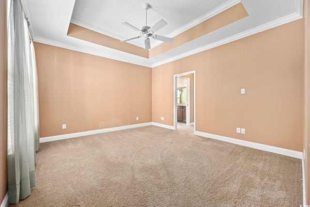 carpeted empty room featuring ceiling fan, a tray ceiling, a textured ceiling, and ornamental molding