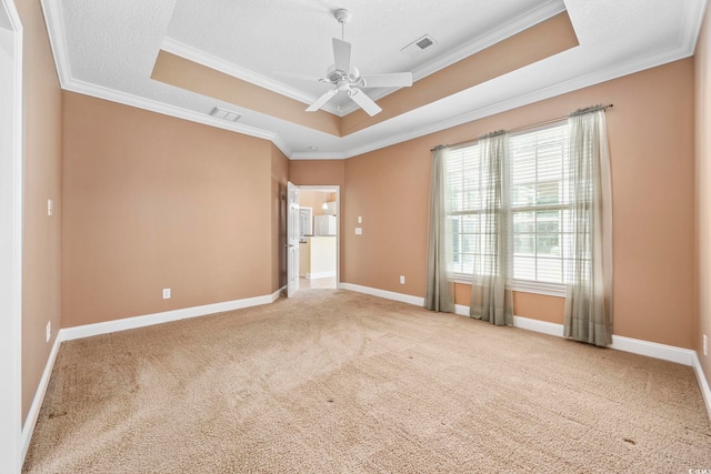 carpeted spare room with ceiling fan, crown molding, and a tray ceiling