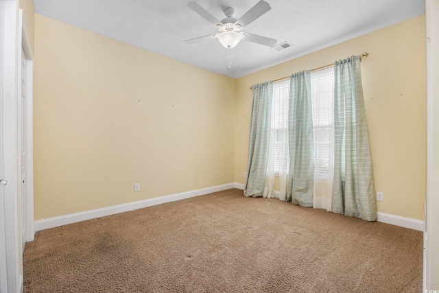 spare room with a textured ceiling, light colored carpet, and ceiling fan