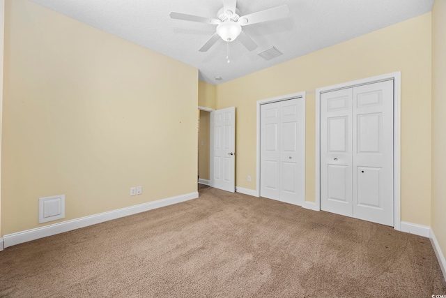 unfurnished bedroom with ceiling fan, carpet flooring, and multiple closets