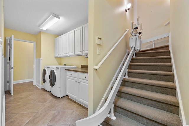 laundry room featuring washing machine and dryer, cabinets, and light tile patterned floors