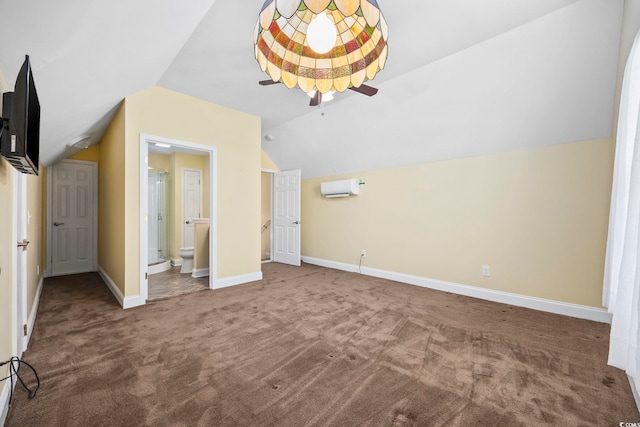 interior space with connected bathroom, lofted ceiling, a wall mounted air conditioner, and carpet floors